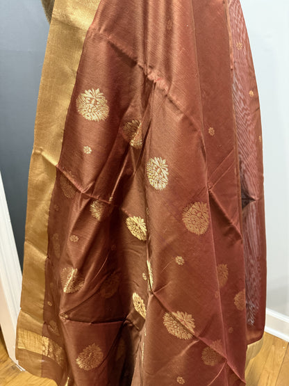 Rust Chanderi Silk saree with golden tissue border and floral buttas.